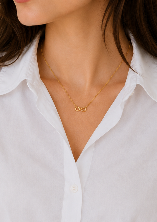 Woman wearing a white shirt and gold necklace against a neutral background